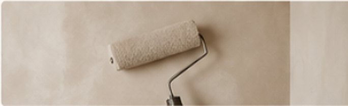 Rouleau de peinture sur un mur beige